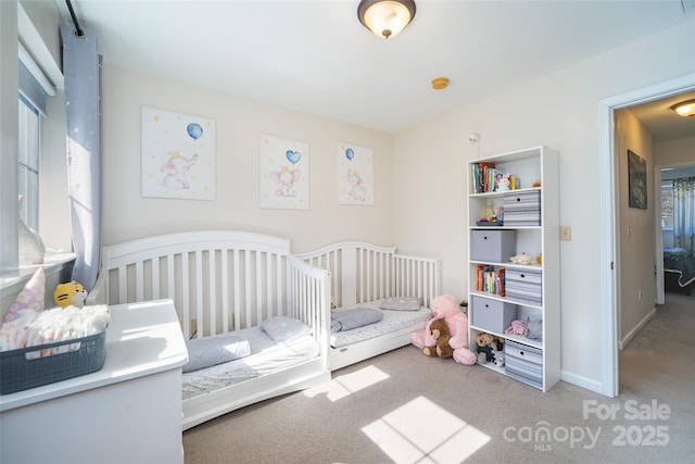 carpeted bedroom featuring baseboards and a crib