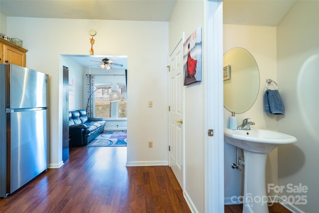 hall with baseboards, dark wood-style flooring, and a sink