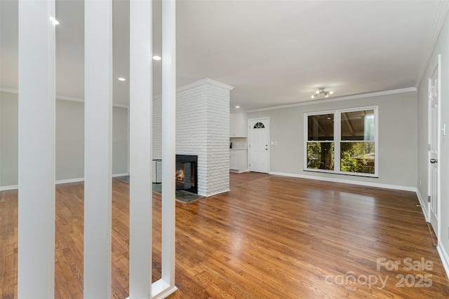unfurnished living room featuring baseboards, a fireplace, wood finished floors, and crown molding
