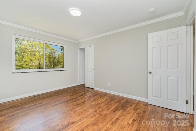 unfurnished room featuring baseboards, crown molding, light wood-style floors, and visible vents