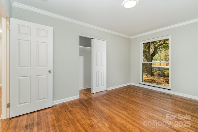 900 E Woodlawn Rd, Charlotte, NC 28209 - unfurnished bedroom with wood finished floors, crown molding, and a closet