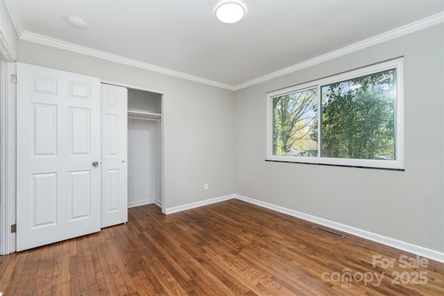 900 E Woodlawn Rd, Charlotte, NC 28209 - unfurnished bedroom with dark wood-style floors, ornamental molding, and a closet
