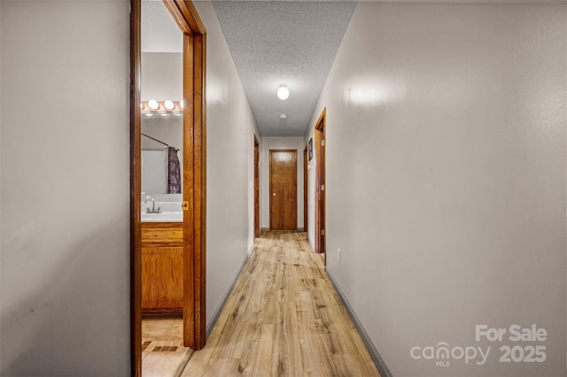 266 Asheland Dr, Ellenboro, NC 28040 - hallway featuring a sink, light wood-style flooring, and a textured ceiling