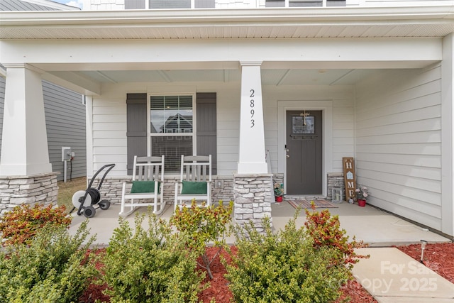 property entrance featuring stone siding and covered porch