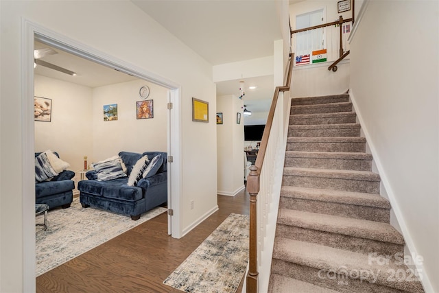 stairs with baseboards, wood finished floors, and ceiling fan