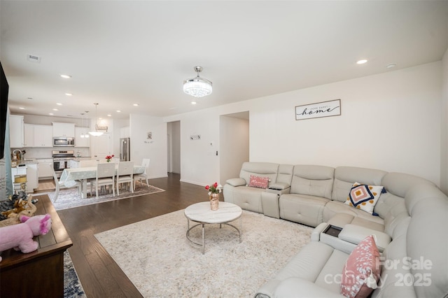 living room featuring baseboards, dark wood-style flooring, visible vents, and recessed lighting