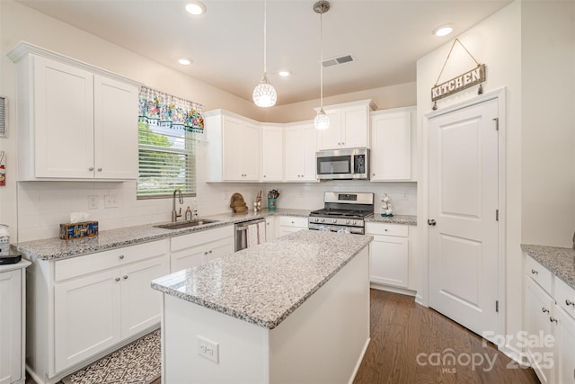kitchen with white cabinets, stainless steel appliances, decorative backsplash, and a sink
