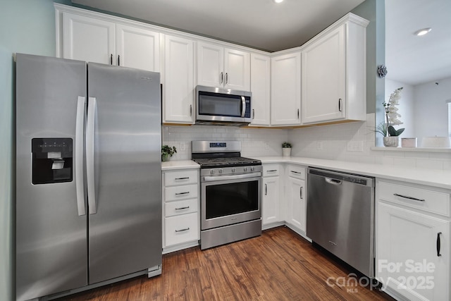 kitchen with decorative backsplash, light countertops, dark wood-style floors, and stainless steel appliances