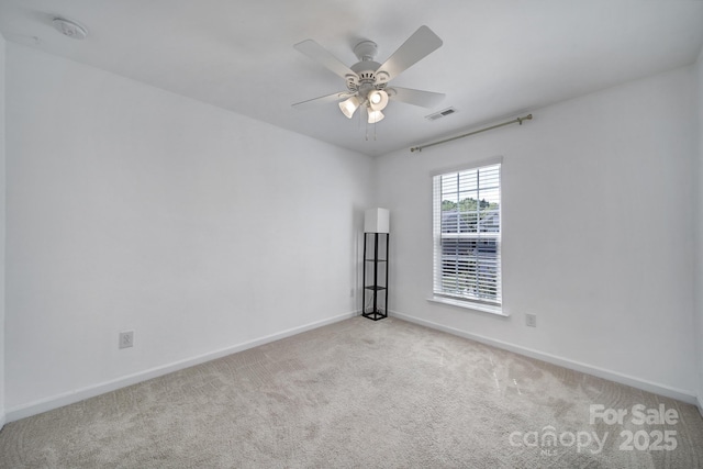 carpeted spare room with visible vents, baseboards, and a ceiling fan