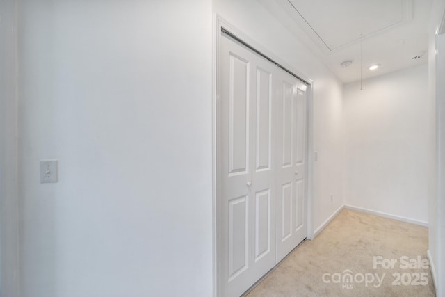 interior space with light carpet, attic access, and baseboards
