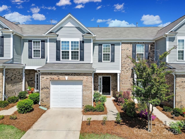 townhome / multi-family property with a garage, brick siding, and concrete driveway
