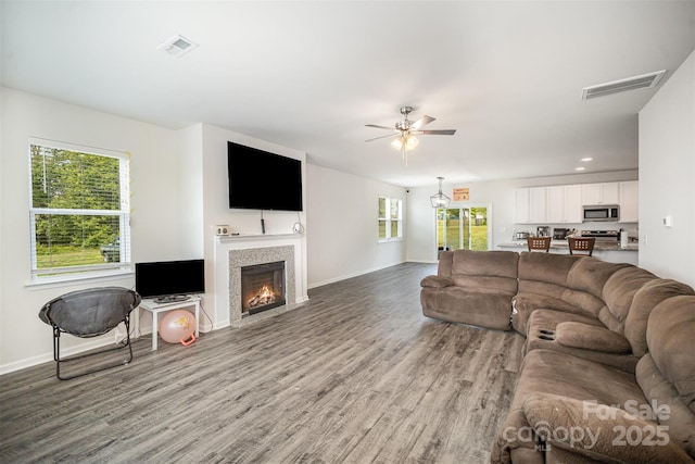 living room with visible vents, ceiling fan, wood finished floors, and baseboards