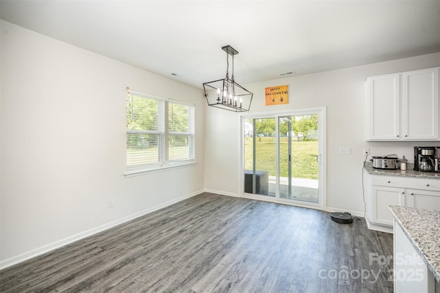 unfurnished dining area with visible vents, baseboards, a notable chandelier, and dark wood-style floors