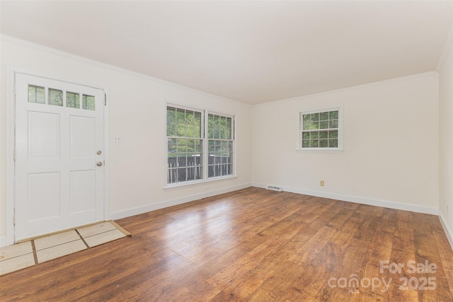 entrance foyer featuring wood finished floors, healthy amount of natural light, crown molding, and baseboards