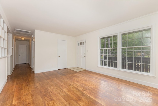 unfurnished room with wood finished floors, baseboards, and ornamental molding