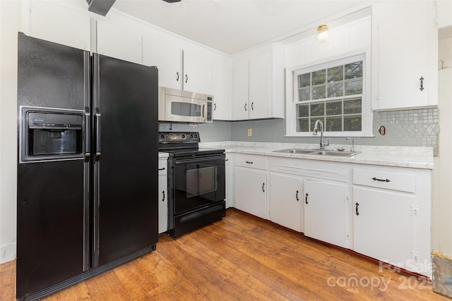 kitchen with black appliances, a sink, light countertops, and white cabinets