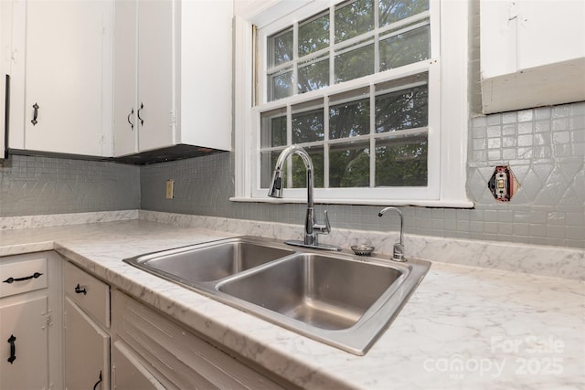 kitchen featuring a sink, light countertops, white cabinetry, and decorative backsplash