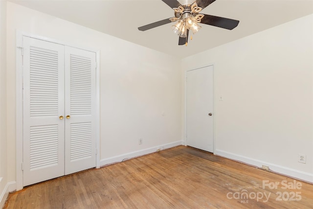 unfurnished bedroom with light wood-type flooring, baseboards, a closet, and a ceiling fan