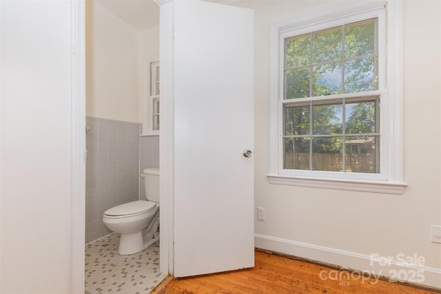 bathroom featuring toilet, tile walls, and wood finished floors