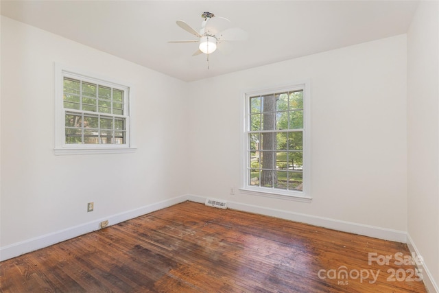 unfurnished room featuring plenty of natural light, baseboards, wood finished floors, and ceiling fan