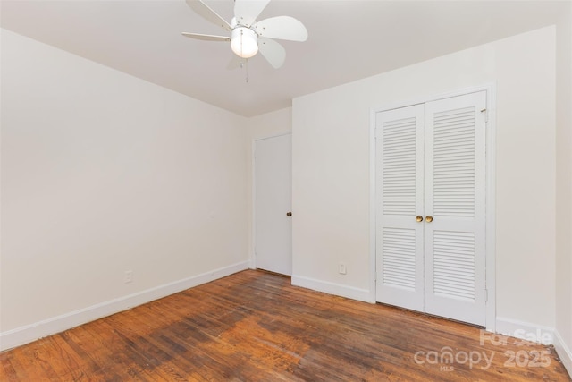 unfurnished bedroom featuring baseboards, wood finished floors, a closet, and a ceiling fan