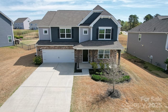 craftsman-style house with stone siding, fence, an attached garage, concrete driveway, and a porch
