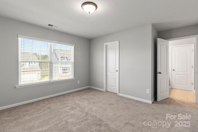 unfurnished bedroom with carpet flooring, baseboards, and visible vents