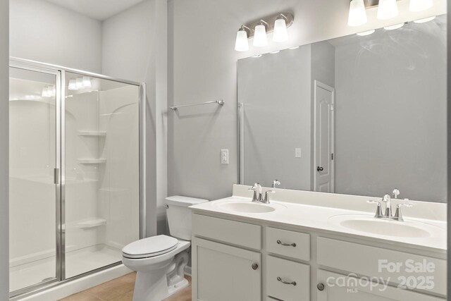 bathroom featuring a stall shower, toilet, and a sink