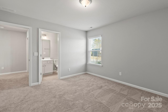 unfurnished bedroom with ensuite bathroom, light colored carpet, visible vents, and baseboards