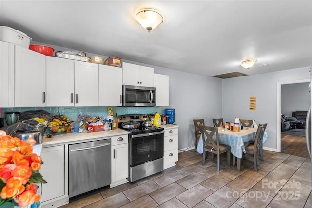 3612 Winterfield Pl, Charlotte, NC 28205 - kitchen featuring white cabinetry, appliances with stainless steel finishes, light countertops, decorative backsplash, and baseboards