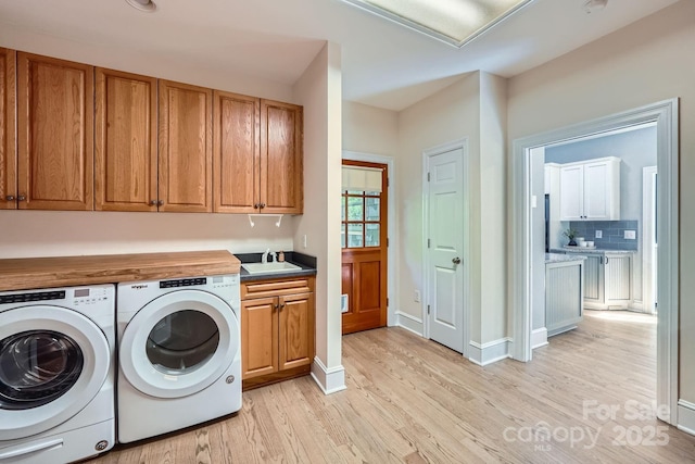 119 Taylor Ct, Mooresville, NC 28117 - clothes washing area with cabinet space, a sink, light wood-style floors, baseboards, and washer and clothes dryer
