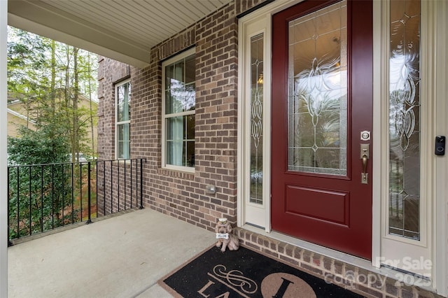 view of exterior entry featuring brick siding and a porch