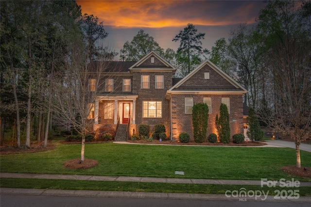 view of front facade featuring concrete driveway, a front yard, and brick siding