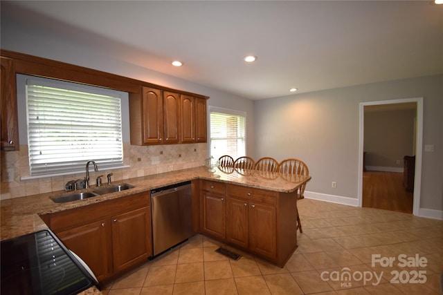 kitchen with tasteful backsplash, stainless steel dishwasher, a sink, and visible vents