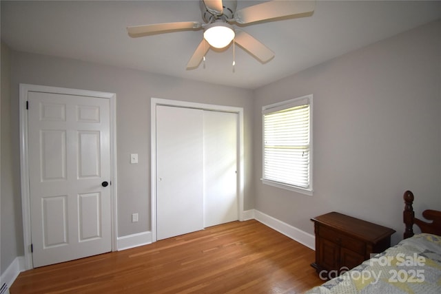 bedroom with a closet, light wood-style flooring, baseboards, and a ceiling fan