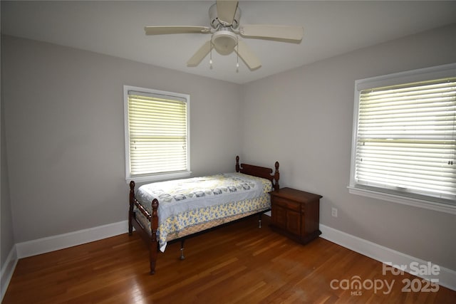 bedroom with baseboards, multiple windows, and wood finished floors