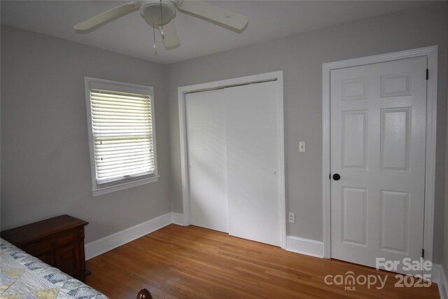 unfurnished bedroom with ceiling fan, a closet, wood finished floors, and baseboards
