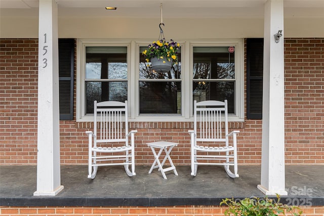 entrance to property with a porch and brick siding