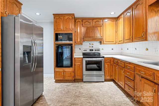kitchen featuring brown cabinets, black appliances, custom exhaust hood, and tasteful backsplash