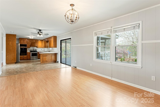 kitchen with light countertops, light wood finished floors, brown cabinets, open floor plan, and stainless steel appliances