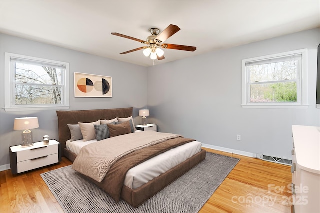 bedroom with baseboards, visible vents, light wood-style flooring, and ceiling fan