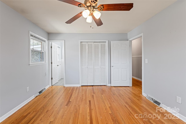 unfurnished bedroom with light wood finished floors, baseboards, visible vents, and a closet