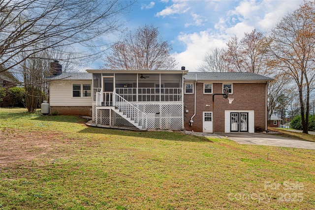back of property featuring a chimney, brick siding, a sunroom, ceiling fan, and a yard