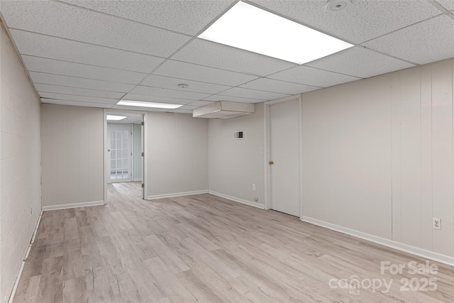 finished below grade area with baseboards, wood finished floors, and a paneled ceiling