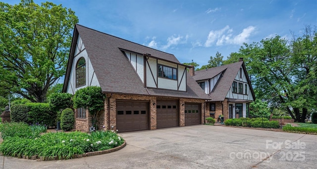 418 3rd St NE, Hickory, NC 28601 - tudor house featuring concrete driveway, an attached garage, stucco siding, brick siding, and roof with shingles