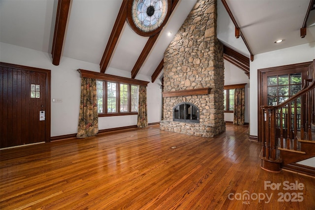 418 3rd St NE, Hickory, NC 28601 - unfurnished living room featuring baseboards, a stone fireplace, wood finished floors, and beam ceiling