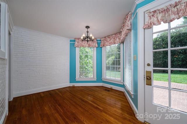 418 3rd St NE, Hickory, NC 28601 - unfurnished dining area featuring baseboards, visible vents, a chandelier, brick wall, and hardwood / wood-style floors