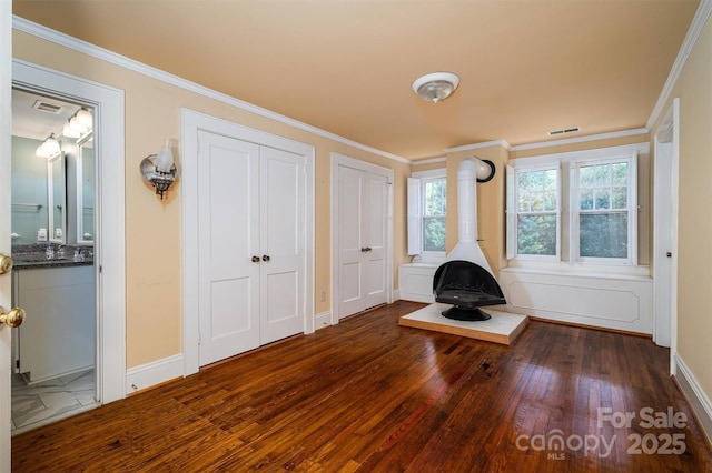 418 3rd St NE, Hickory, NC 28601 - unfurnished living room featuring a wood stove, crown molding, hardwood / wood-style flooring, and visible vents