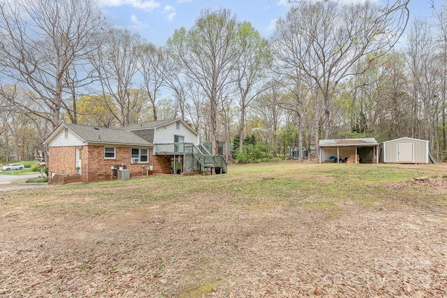 view of yard with an outdoor structure, a detached carport, central AC, a deck, and a storage unit