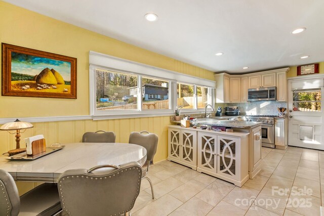 2 Bevlyn Dr, Asheville, NC 28803 - kitchen with stainless steel appliances, light tile patterned floors, decorative backsplash, a peninsula, and cream cabinets